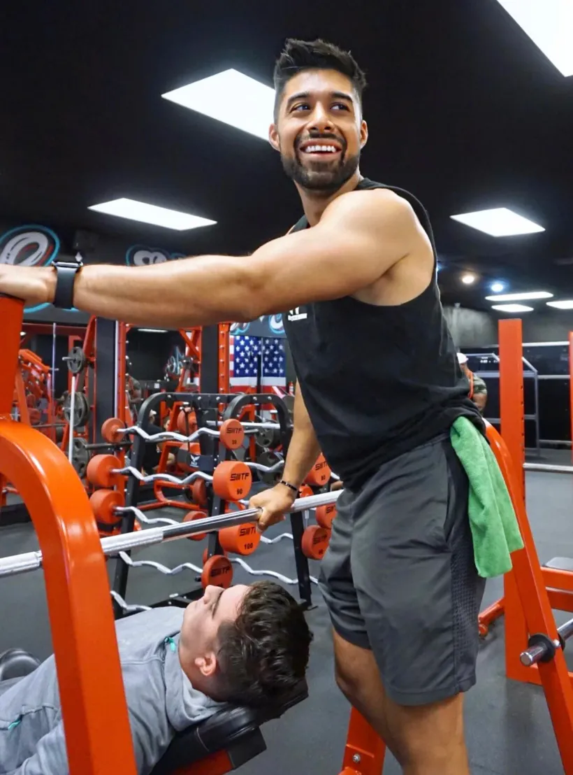 Coach Nathan Castillo spotting a client at the gym